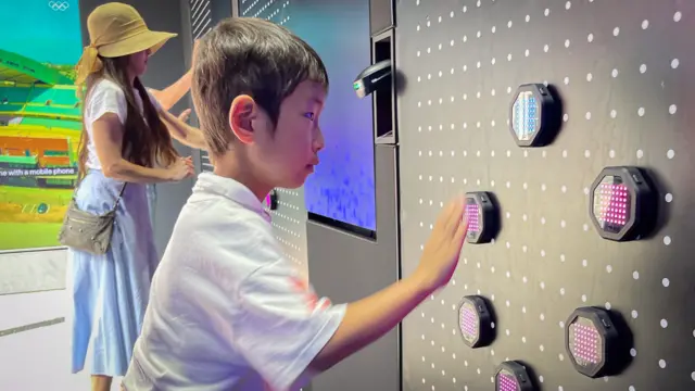 A young boy plays a game where he has to touch illumated sensors in front of him